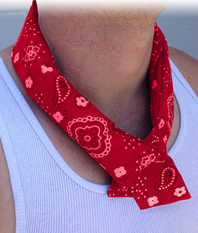 A person wearing a white tank top with a black and green camouflage cooling bandana wrapped around their neck.